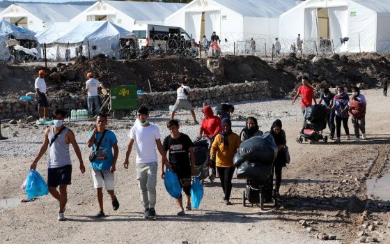 Migrants walk with their belongings as they make their way to the Kara Tepe refugee camp on the Greek island of Lesbos Oct. 14. (CNS/Reuters/Elias Marcou)