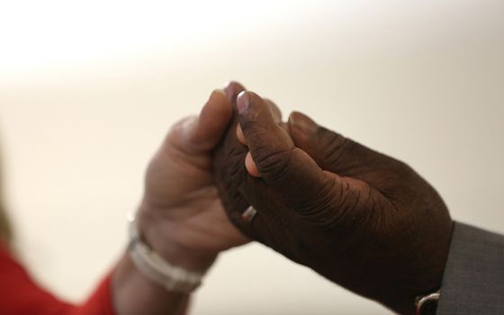 A woman and man join hands during the Our Father during Mass. (CNS/Bob Roller)