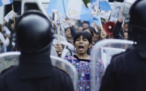 Backs of riot police seen, faces of people protesting