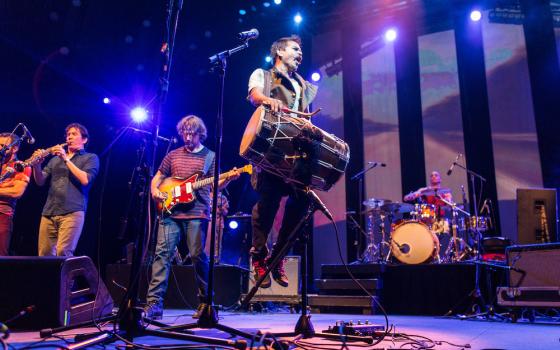 Holding the dhol (drum), Sunny Jain, founder of Red Baraat, jumps during a concert. (Courtesy of Red Baraat/Sachyn Mital)