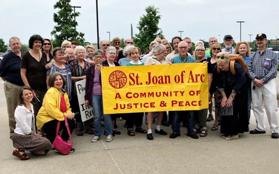 Displaying a banner for St. Joan of Arc Parish, members of St. Joan of Arc/WAMM Peacemakers hold a monthly prayer vigil. (Provided photo)