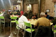 People enjoy dinner at Bishop Sullivan Center's One City Café, a restaurant-style community kitchen offering free meals in Kansas City, Missouri, as volunteers and staff serve them Feb. 26. (NCR photo/Maria Benevento)