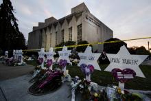 Small markers bear the names of the killed, in the background is the synagogue still marked with crime scene tape,