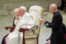 Pope Francis coughs as Msgr. Pierluigi Giroli reads his catechesis during his weekly general audience in the Paul VI Audience Hall at the Vatican Feb. 12, 2025. Seated next to the pope, Msgr. Leonardo Sapienza, an official of the Prefecture of the Papal Household, looks on. (CNS photo/Lola Gomez)