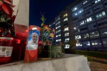 Votive candles, including some bearing a photo of Pope Francis, are seen on the base of a statue of St. John Paul II outside Rome's Gemelli hospital Feb. 15, 2025. (CNS photo/Pablo Esparza)