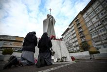 Nuns pray next to the statue of St. John Paul II outside Rome's Gemelli Hospital Feb. 20, 2025, where Pope Francis is admitted for treatment for a respiratory infection. The Vatican press office said early Feb. 20 that the pope had a peaceful night, "got up and had breakfast in an armchair." (OSV News photo/Guglielmo Mangiapane, Reuters)