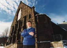 Fr. James Callan, then pastor of Corpus Christi Parish in Rochester, N.Y., poses in front of the church in 1997. (NCR file photo)